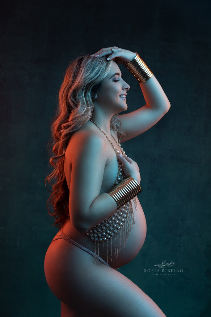 mom is illuminated in blue and orange gel lighting for a pregnancy photoshoot