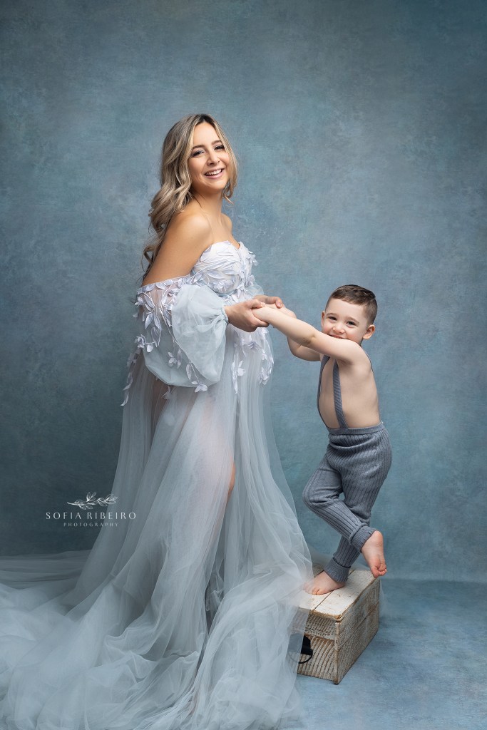 mom plays with her toddler son while smiling at the camera during a maternity session in clark nj