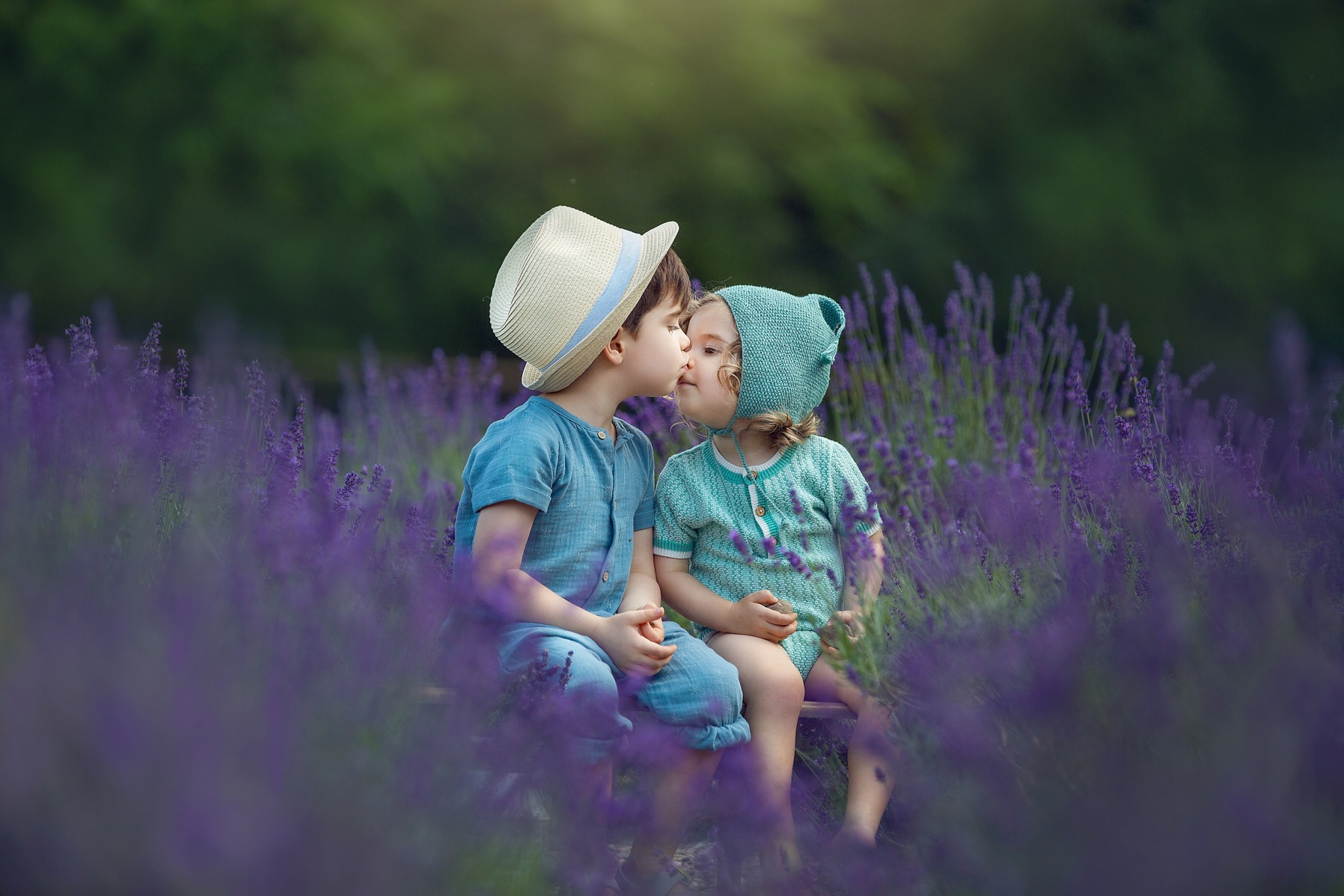 Toddler brother and sister kiss while sitting on a wooden bench in a lavender farms nj