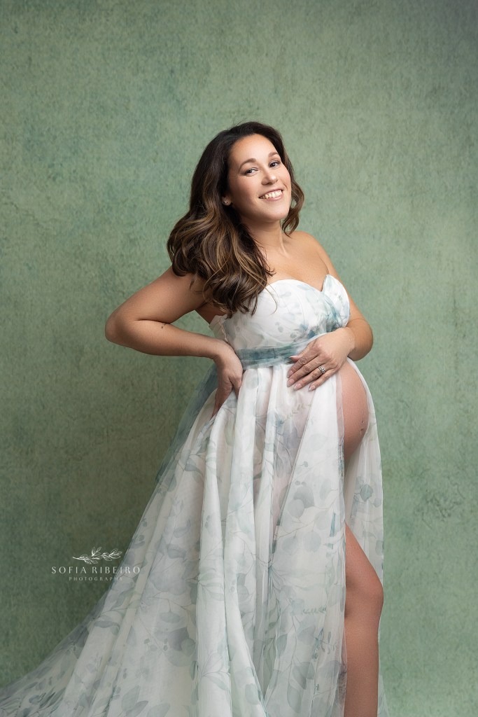 mom smiles at the camera, hands on hips and belly during a portrait maternity session