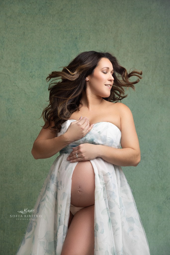 mom swishes her hair in between shots during a maternity photo session