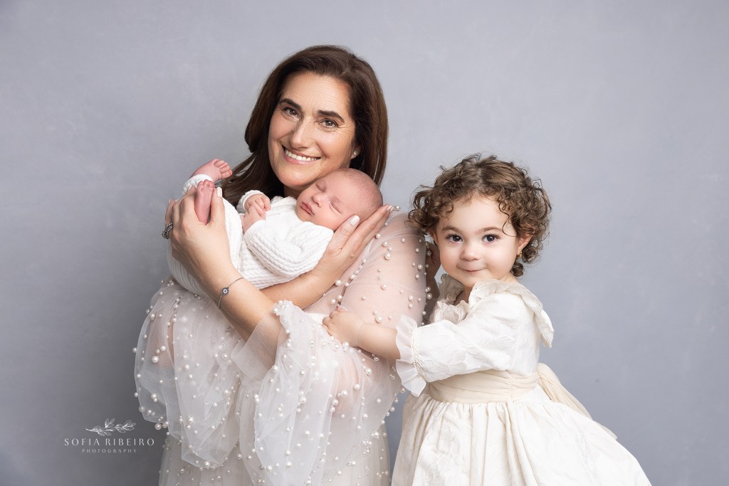 grandma cradles her grandbaby and big sister during baby's newborn session