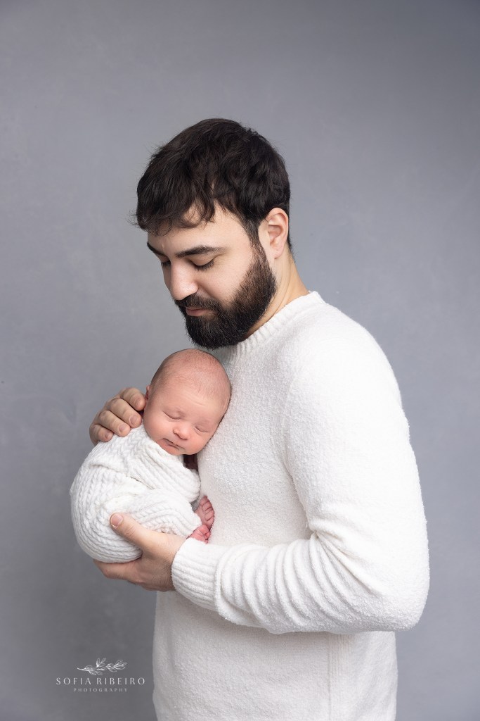 dad holds his baby close to his chest during a newborn session