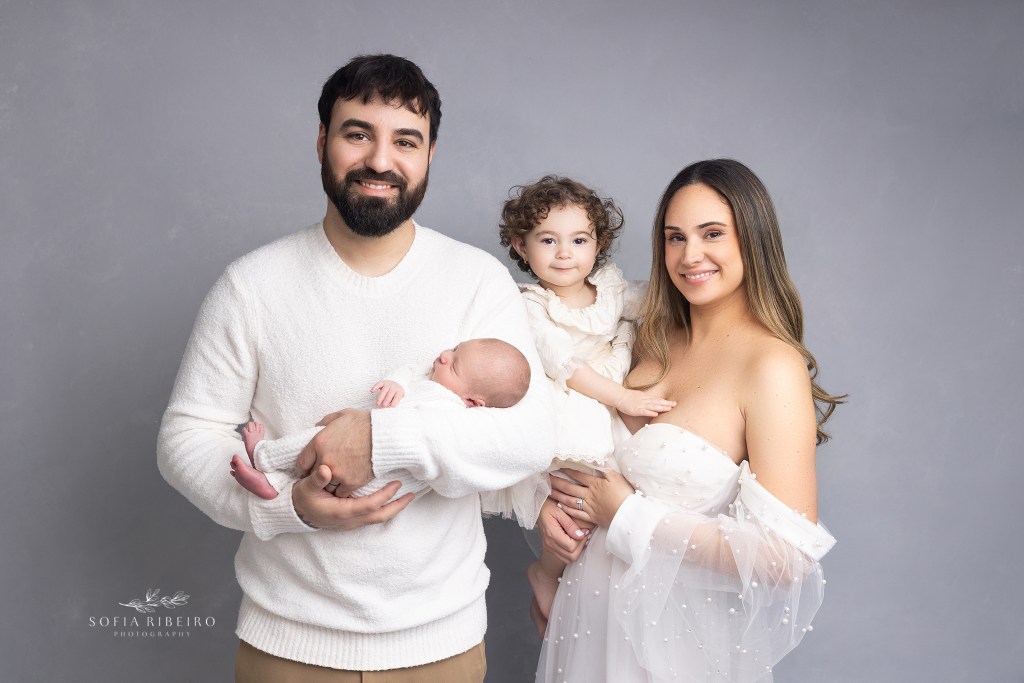big sister squeals at the camera during a family pose at her baby brother's newborn session in nj