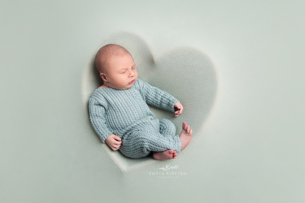 newborn baby boy in mint green posed in a heart prop during a newborn photography session in nj