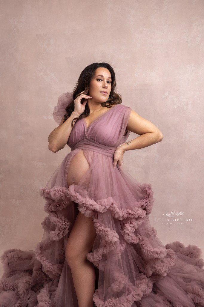 pregnant mom holds her belly wearing a pink down during a maternity session in new jersey