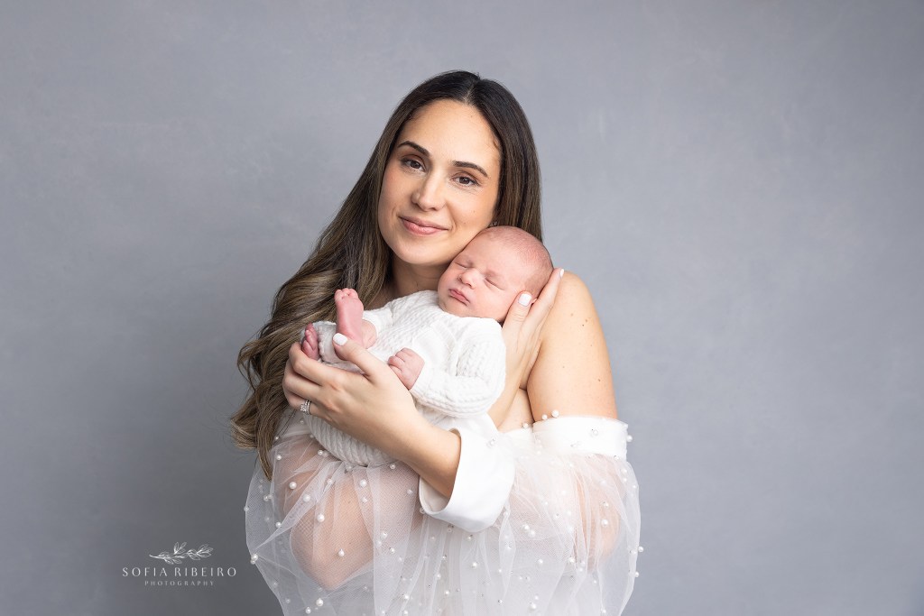 mom holds her new baby boy and smiles at the camera