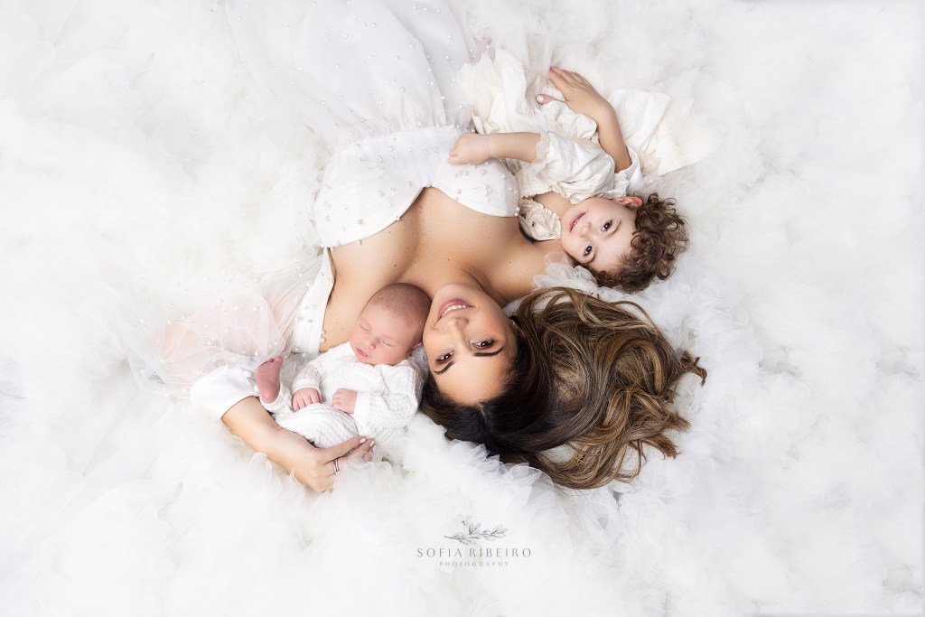 mom in white pearl dress poses with her two babies during a newborn photography studio session in nj