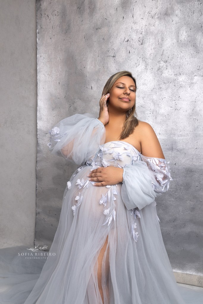 mom poses in a blue dress against a silver backdrop during a photo session with a roselle park nj maternity photographer