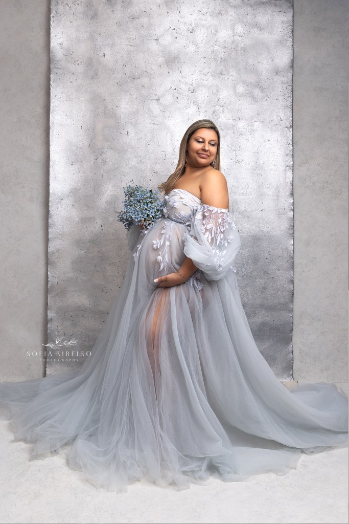 mom poses in a blue dress against a silver backdrop during a photo session with a roselle park nj maternity photographer