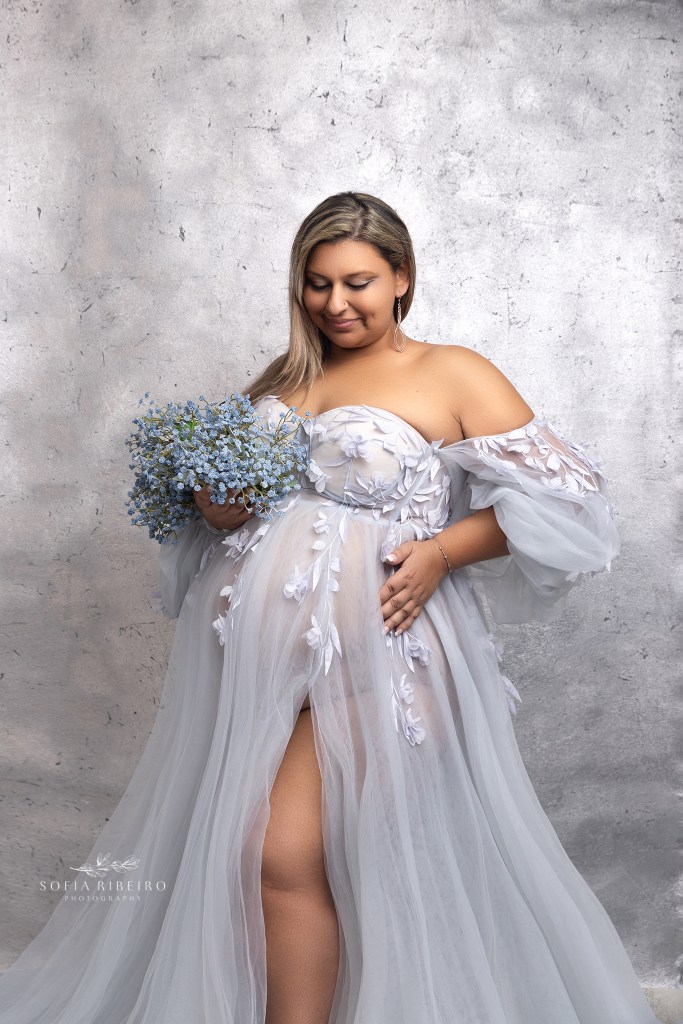 mom poses in a blue dress against a silver backdrop during a photo session with a roselle park nj maternity photographer