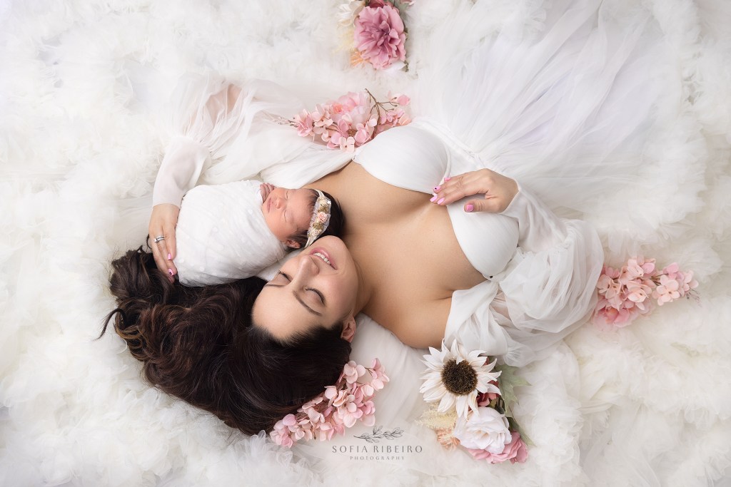 mom lies with baby wrapped in white during a newborn photo session in colonia nj