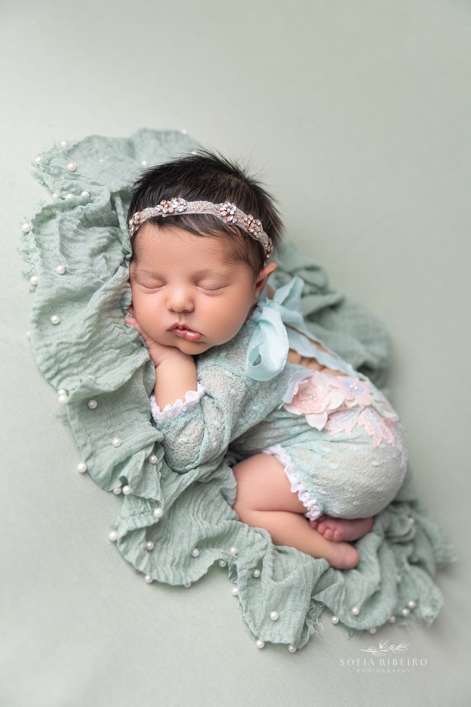 a newborn baby girl is photographed in a mint and pink outfit with a cranford nj newborn photographer
