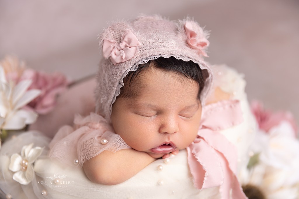 baby girl is posed in a basket prop with a pink teddy bear outfit with a cranford nj newborn photographer