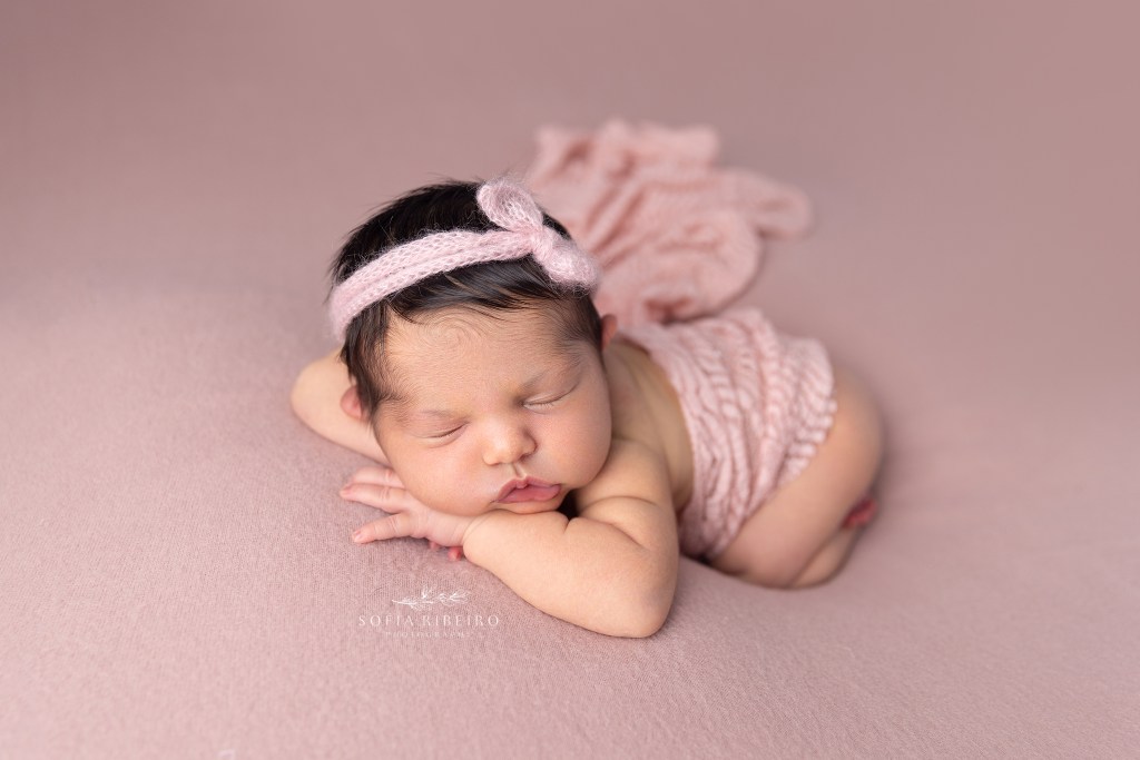 baby girl is dressed in a pink outfit and laid on a blanket during a session in cranford nj