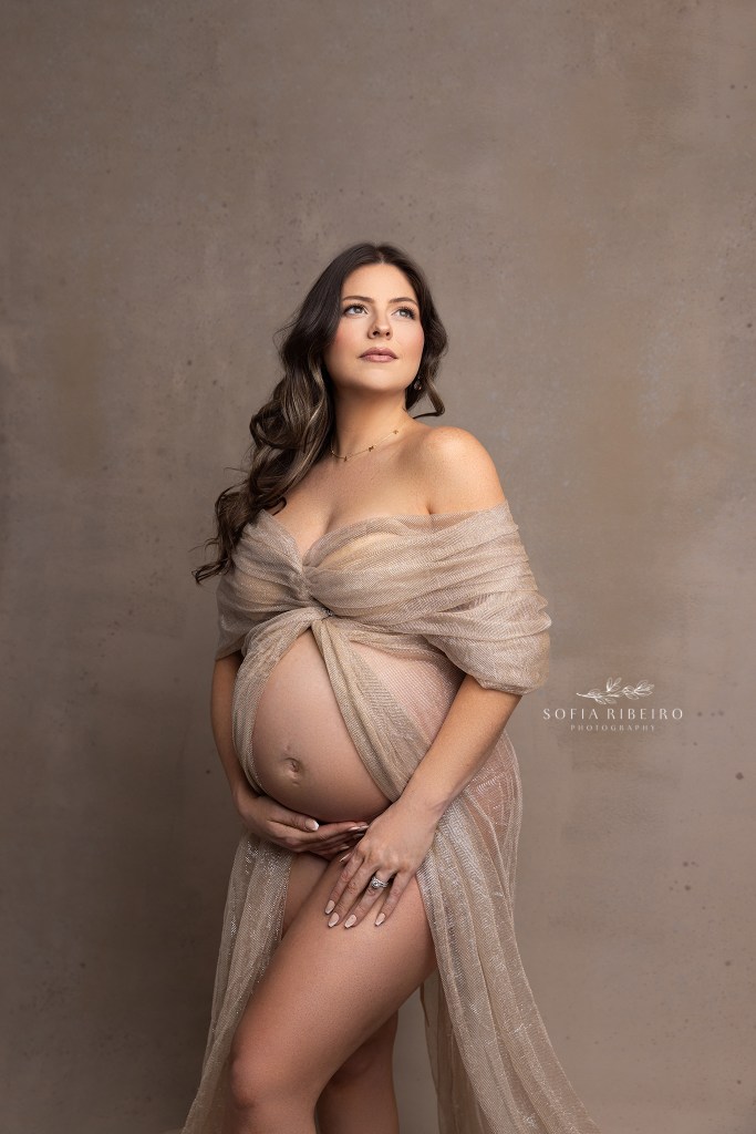 mom is draped in golden shimmery fabric open in front to show her baby bump with a dover nj maternity photographer