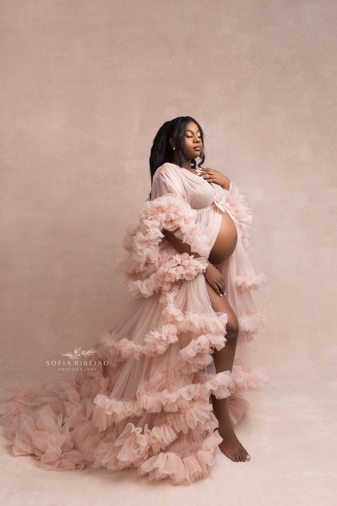 expectant mom strike a power pose in a layered pink tulle dress during a maternity session in nj