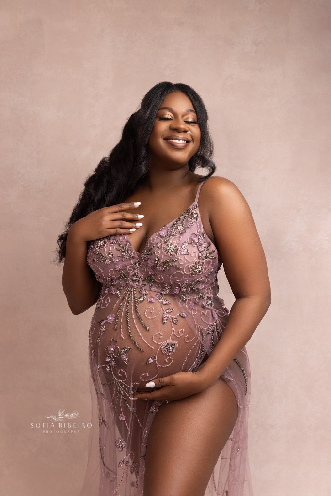 expectant mom is radiant showing off her baby bump in a sheer beaded pink dress during a maternity session in nj