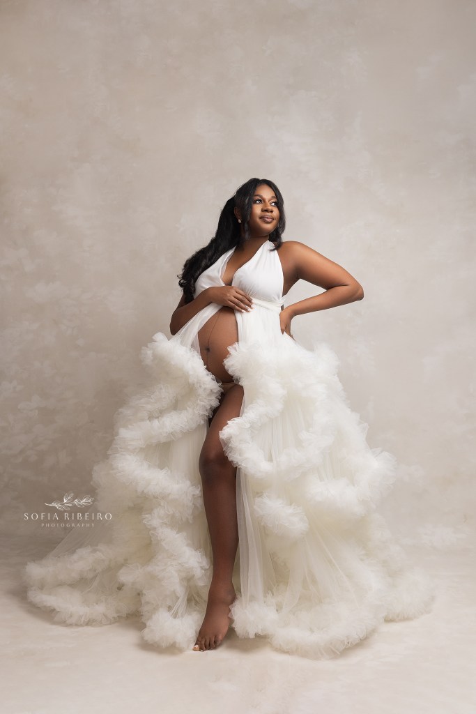 mom poses with one hand on her belly and another on her hip during her maternity session in nj
