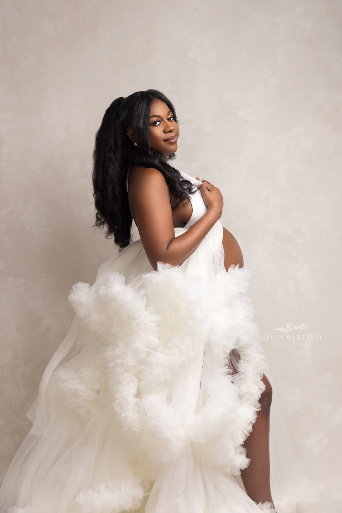 mom looks to the camera in a white ruffled tulle gown during her maternity session with an lgbtq maternity photography studio in nj