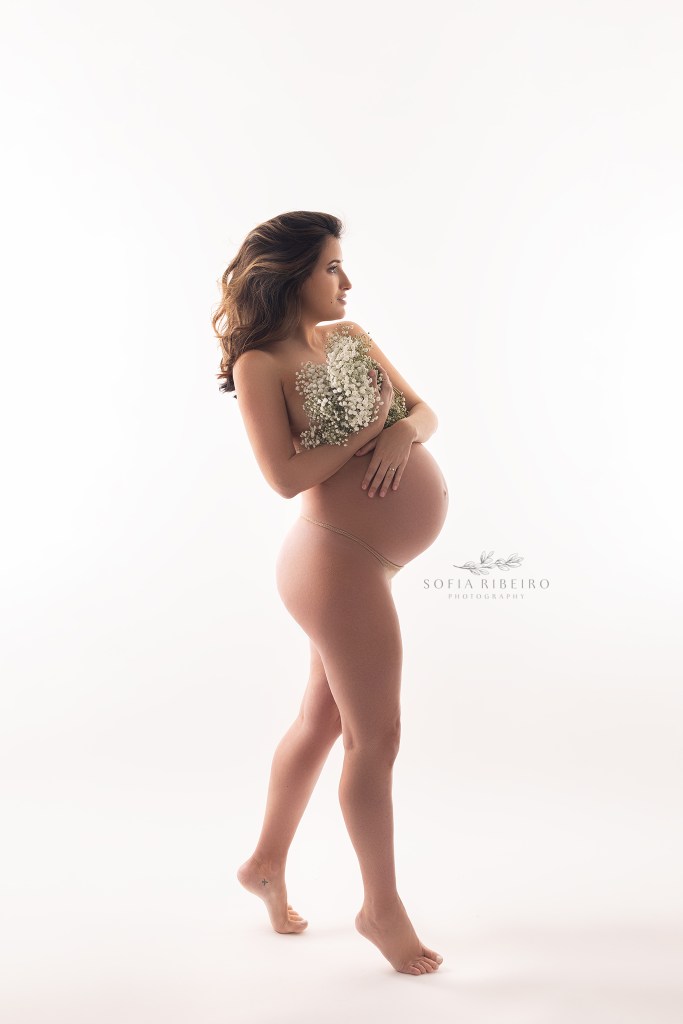red bank nj maternity photographer captures a silhouette of a pregnant mom against a white backdrop holding flowers
