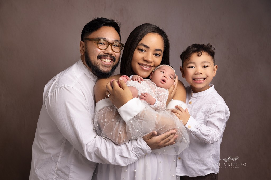 a family of four dressed in white celebrated their new baby girl together during a newborn session in randolph nj