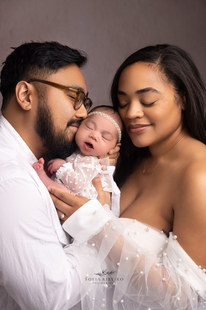mom and dad snuggle baby girl close during a newborn photo session