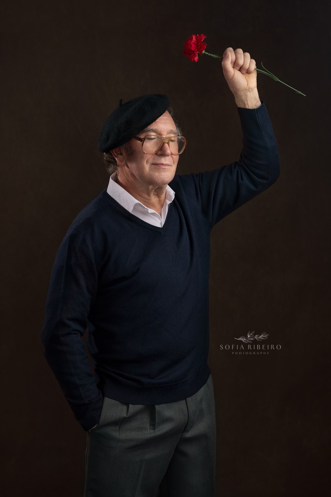 man posing as jose afonso inspiration with a carnation in the air to celebrate 25 de abril 50th anniversary. Modelo a fazer de jose afonso, com cravo na mao em homenagem ao cinquentenario de 25 de abril, portugal's carnation revolution