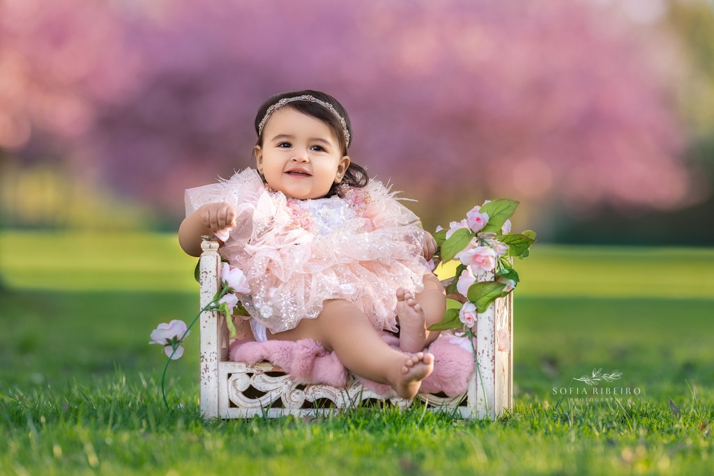 baby girl poses in a bed prop in an outdoor cherry blossom session