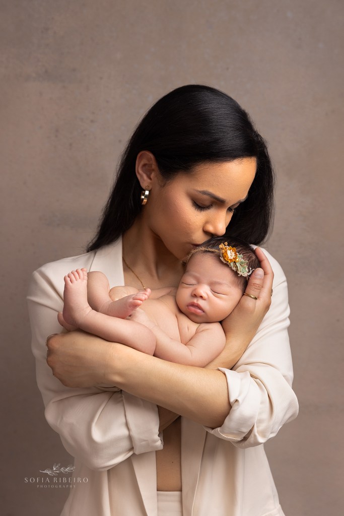 mom kisses baby girl sweetly on the head during their newborn photo session in englewood nj