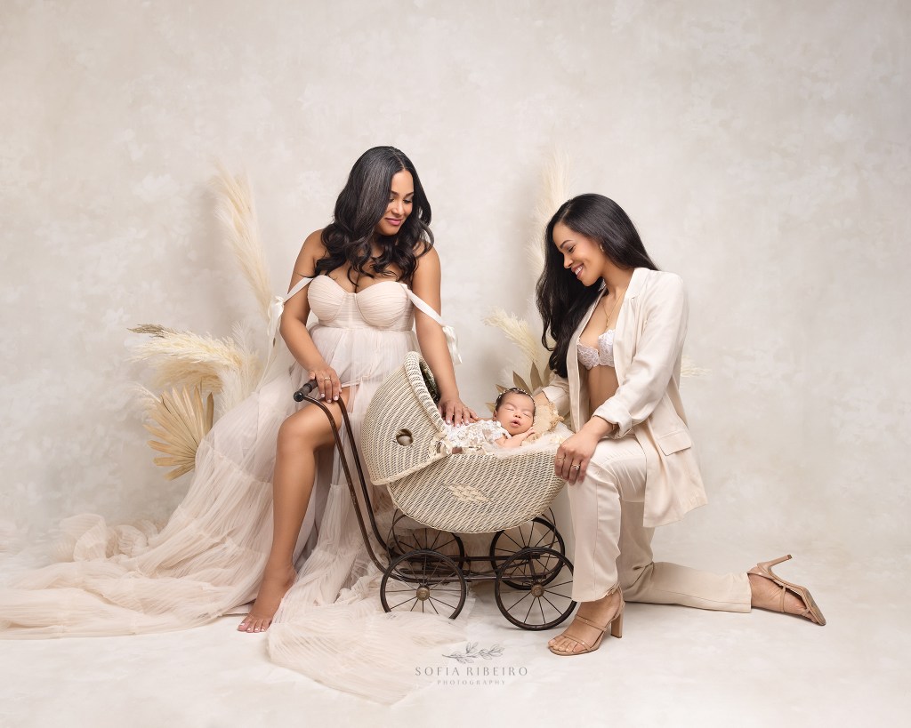 two moms lovingly pose with their baby girl during a newborn photo session in englewood nj