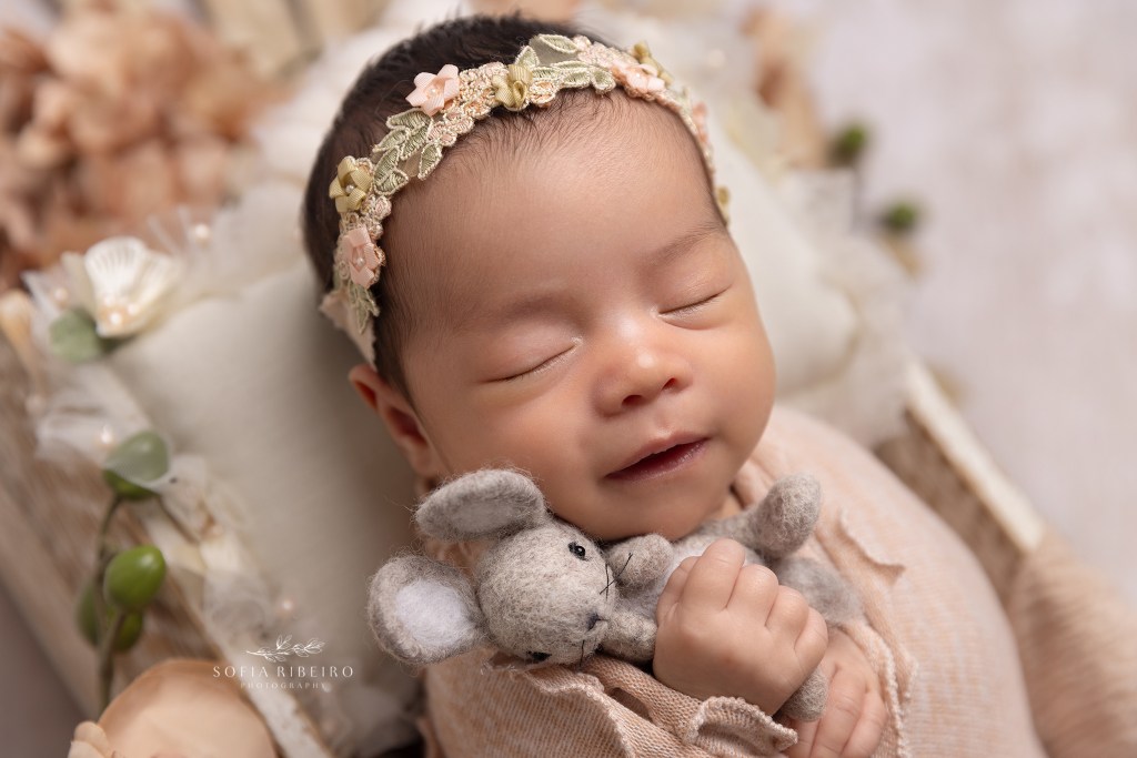 baby girl smiles with a bunny prop during a photo session with englewood nj newborn photographer
