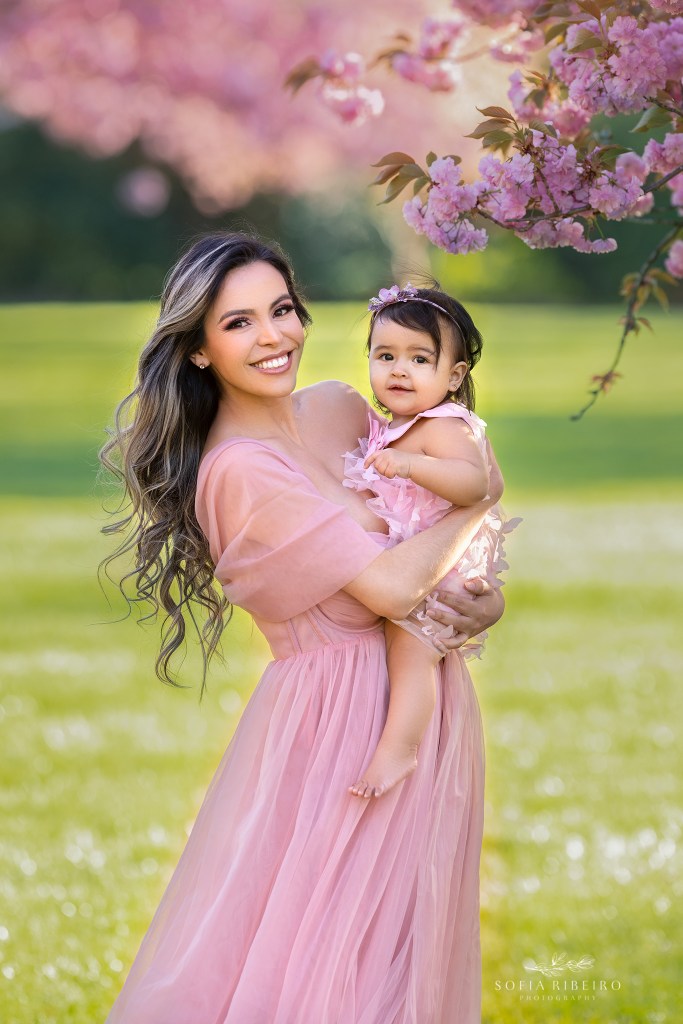 mom poses with her bay girl in cherry blossom trees