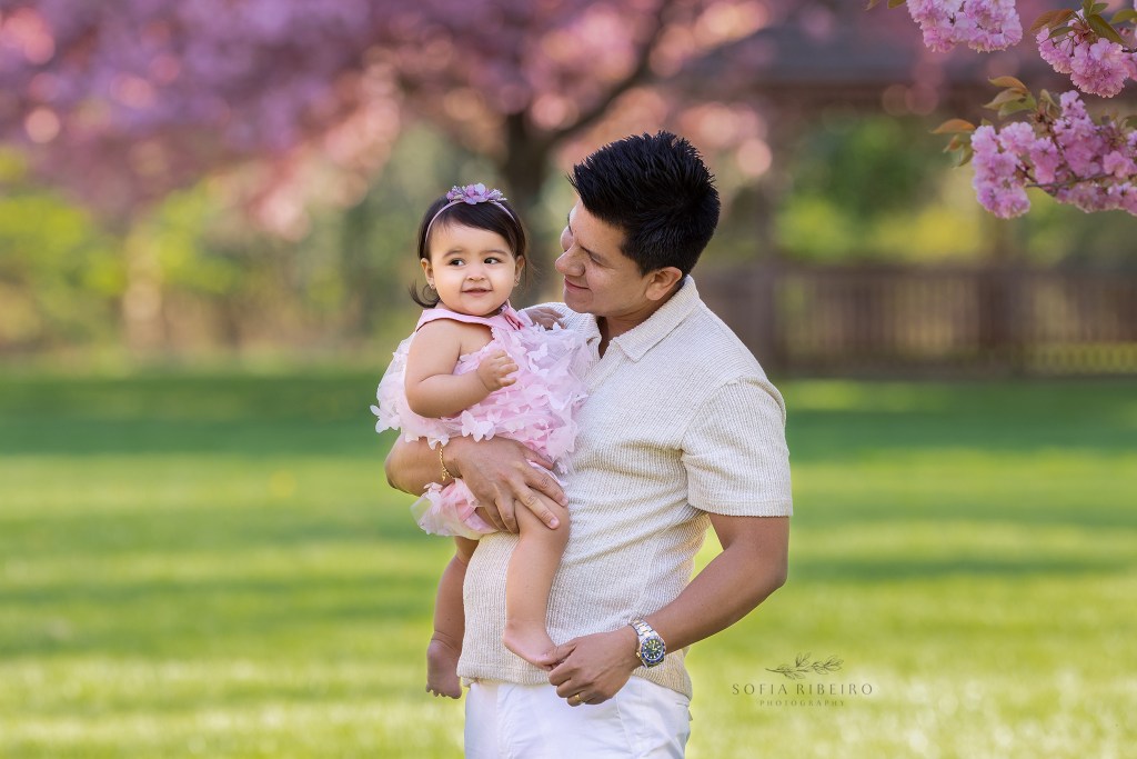 dad looks at his baby girl, smiling in pink
