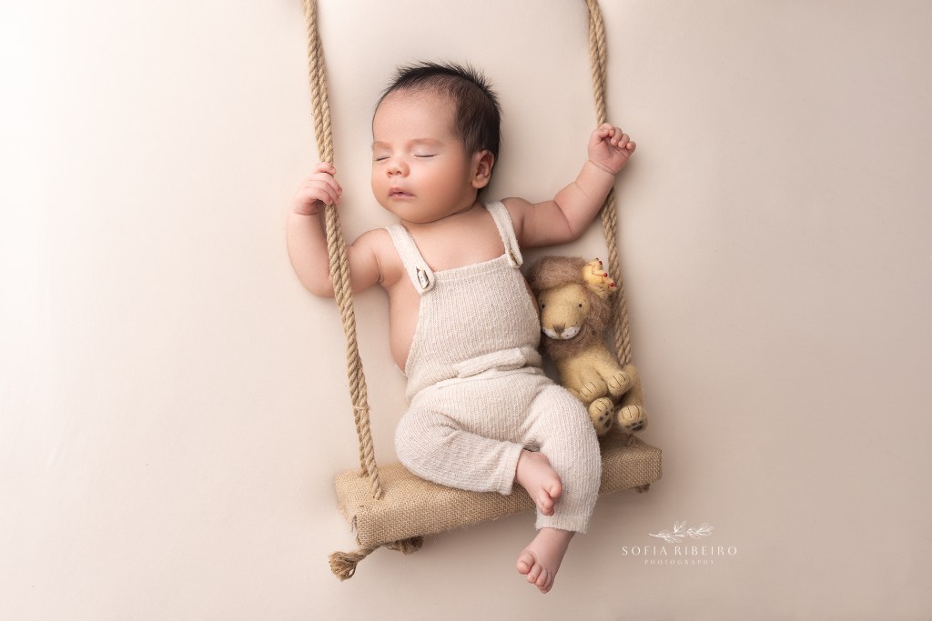 newborn boy is posed on a swing prop during a photo session