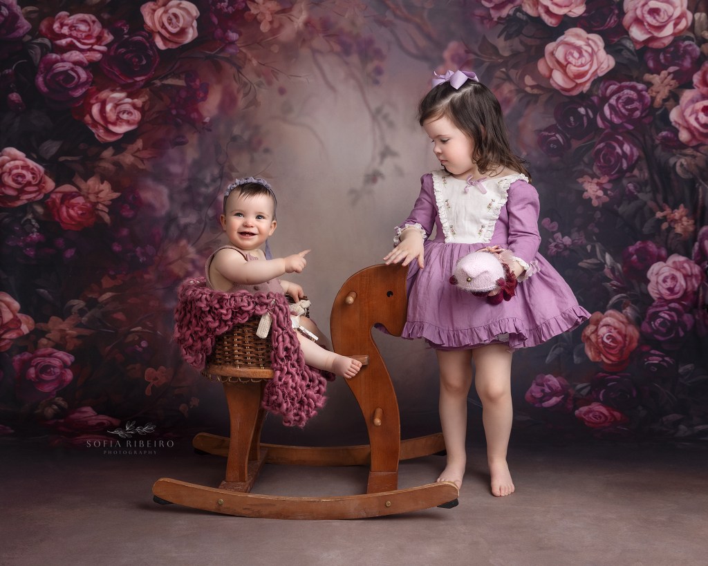 sister play on a vintage horse prop with a purple flower backdrop in westfield nj