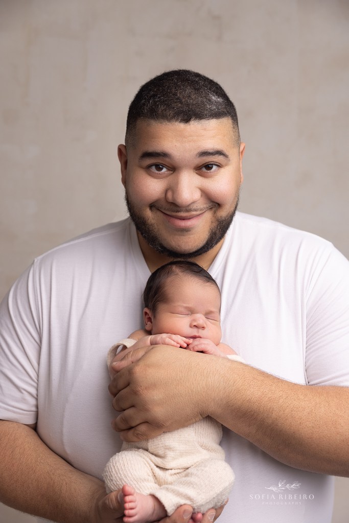 dad smiles proudly while cuddling his baby boy during a newborn session with wharton nj newborn photorapher