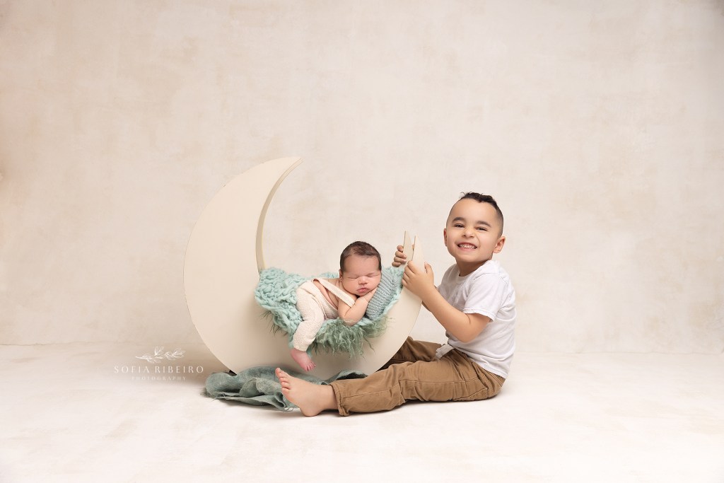 big brother smiles proudly at the camera during a newborn session with a wharton nj newborn photographer