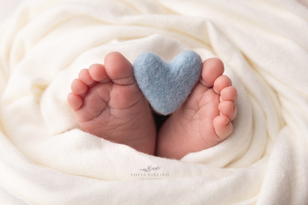 baby feet holding a felted heart during a newborn session