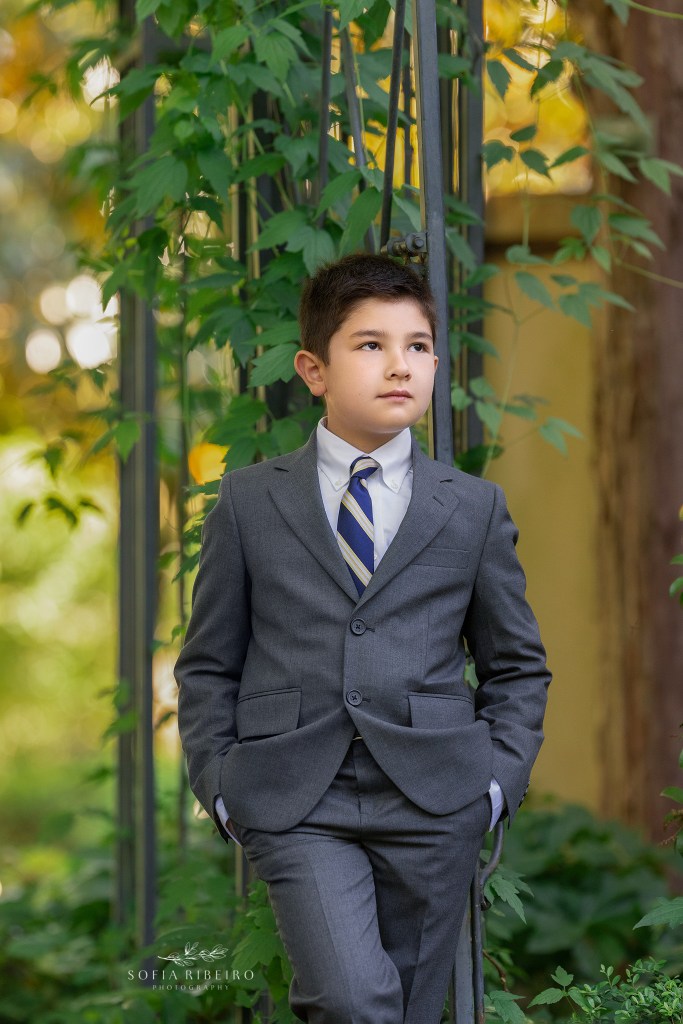 child poses against an arbor in his communion suit in morristown nj
