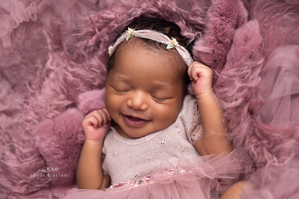 newborn baby girl smiles for a portrait in her sleep