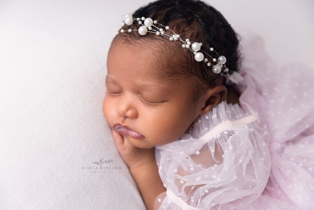 a closeup of a newborn baby girl wearing a pearl headband during a photo session in n j