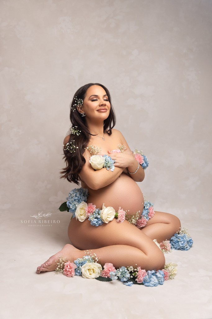 mom's belly is decorated with pink and blue flowers to highlight that she is expecting twins during her maternity session portraits