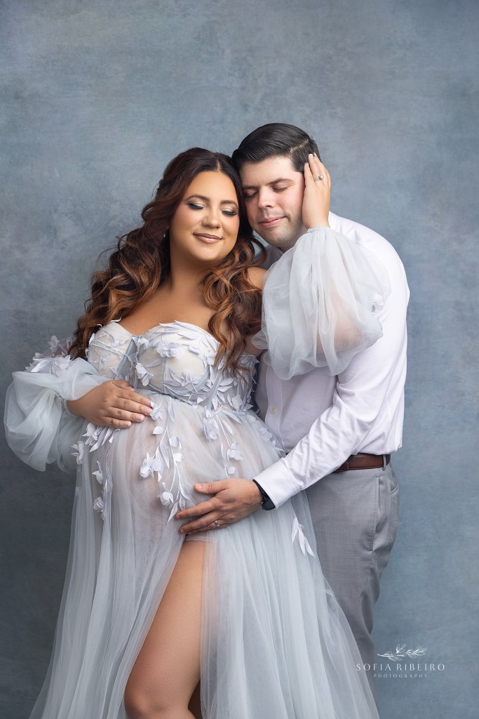 mom and dad share a loving embrace while cradling the baby bump during a maternity photo session