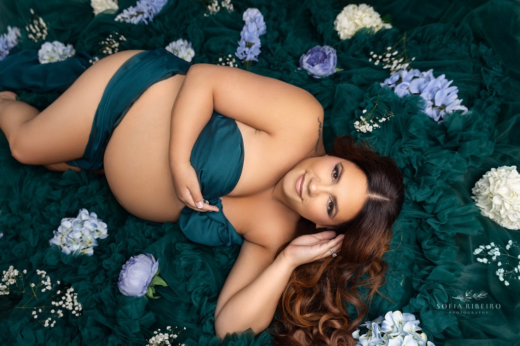 mom to be is nestled in a cradle of tulle and flowers during her maternity photo session in neptune nj