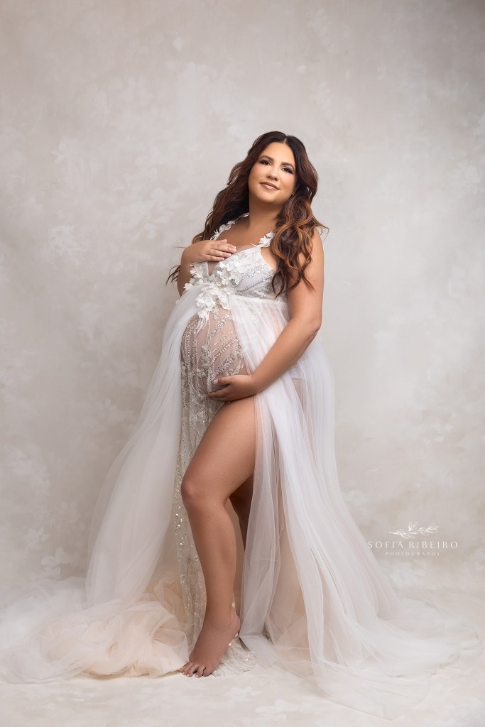 mom places a hand over her heart and another under her belly, welcoming the joys of her impending birth during a photo session in neptune nj