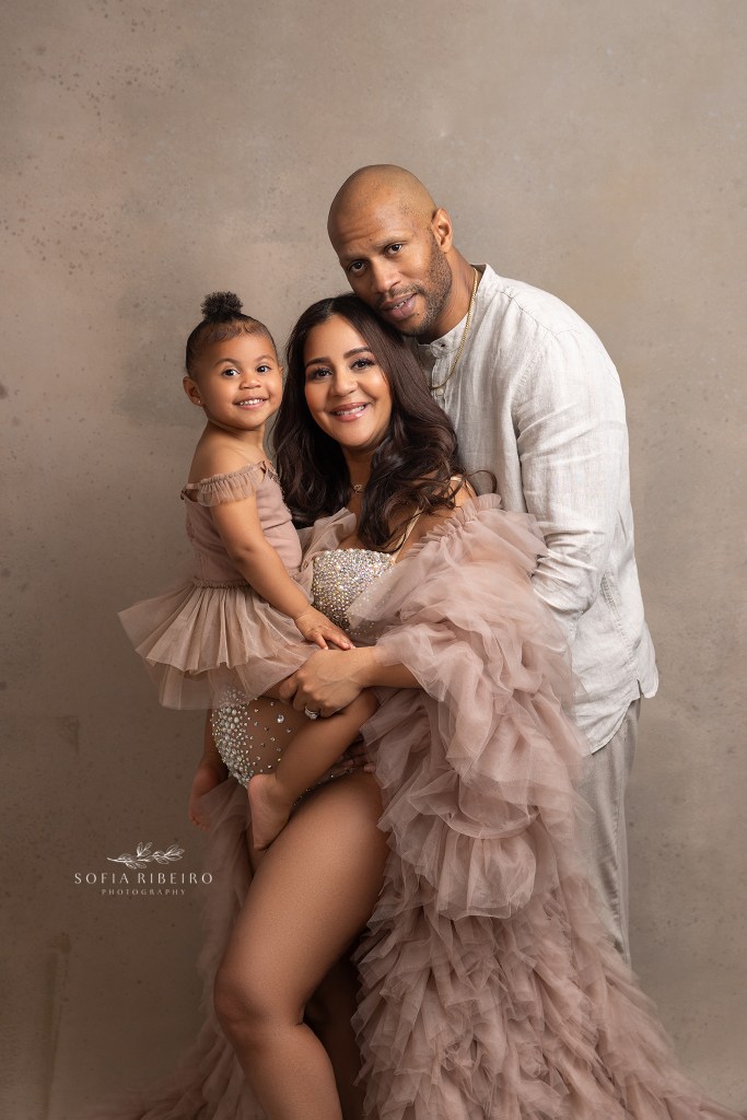 a family of three pose with mom's expectant belly