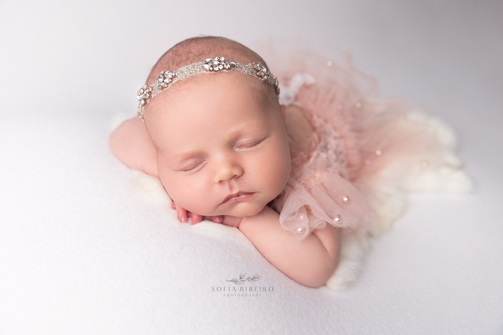 baby girl looks perfect in a pink tutu and tulle outfit on a white backdrop