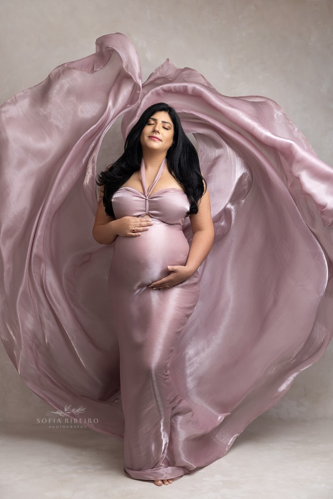 an expectant mom poses in a flowing pink fabric during her maternity session in port reading nj