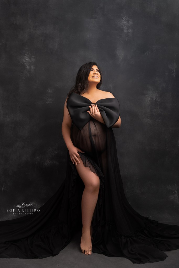 a black bow is draped above moms bump during a maternity portrait